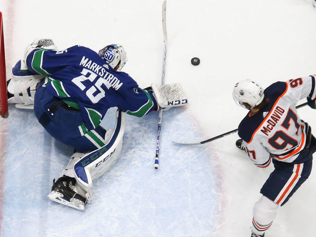 VANCOUVER, BC - DECEMBER 23: Vancouver Canucks Goalie Jacob Markstrom (25) makes a save while watched by Edmonton Oilers Center Connor McDavid (97) during their NHL game at Rogers Arena on December 23, 2019 in Vancouver, British Columbia, Canada.