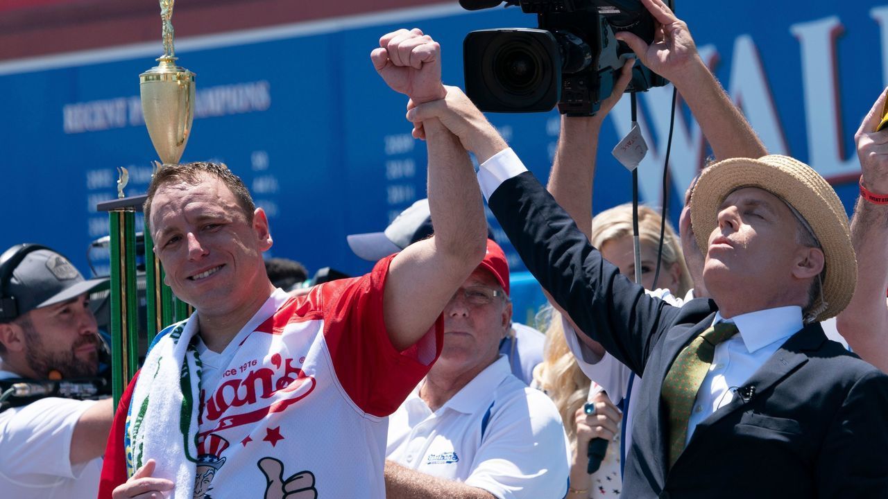 Joey Chestnut (L) has his arm raised in the air by George Shea after Chestnut won the 2019 Nathan's Famous Fourth of July hot dog eating contest on Coney Island on July 4, 2019 in New York.