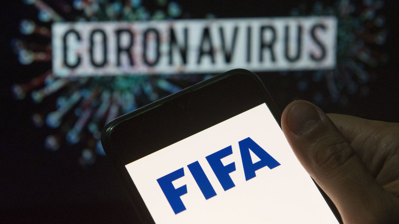 CHINA - 2020/03/24: In this photo illustration the Fédération Internationale de Football Association (FIFA) logo seen displayed on a smartphone with a computer model of the COVID-19 coronavirus on the background. (Photo Illustration by Budrul Chukrut/SOPA Images/LightRocket via Getty Images)