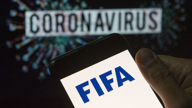 CHINA - 2020/03/24: In this photo illustration the Fédération Internationale de Football Association (FIFA) logo seen displayed on a smartphone with a computer model of the COVID-19 coronavirus on the background. (Photo Illustration by Budrul Chukrut/SOPA Images/LightRocket via Getty Images)
