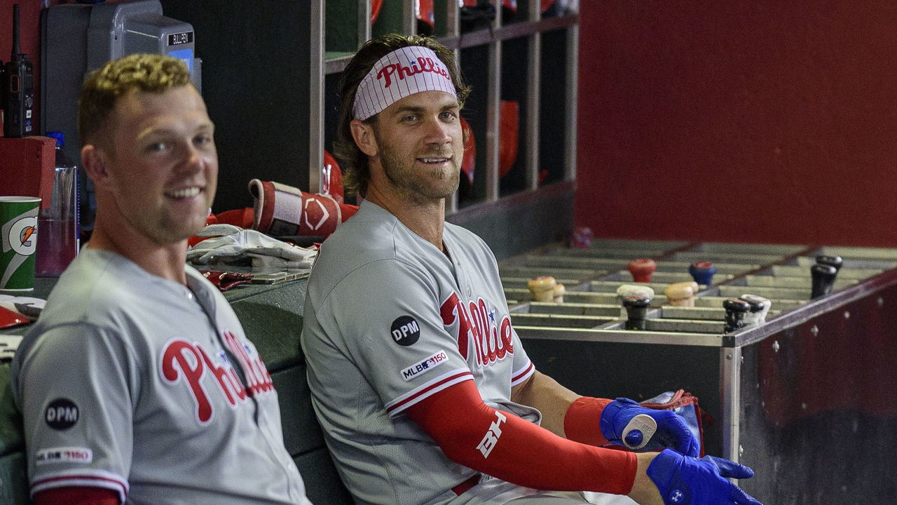 PHOENIX, ARIZONA - AUGUST 05: Rhys Hoskins #17 and Bryce Harper #3 of the Philadelphia Phillies sit in the dugout prior to the MLB game against the Arizona Diamondbacks at Chase Field on August 05, 2019 in Phoenix, Arizona.