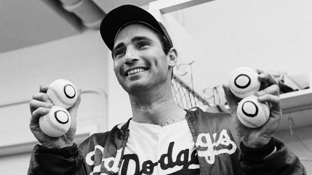 (Original Caption) 9/9/1965-Los Angeles, CA: In the dressing room late 9/9, Dodgers' pitcher Sandy Koufax holds up four balls with zeros on them, one for each of his no-hitters. Koufax threw his fourth no-hitter and downed the Chicago Cubs, 1-0, with a perfect game.