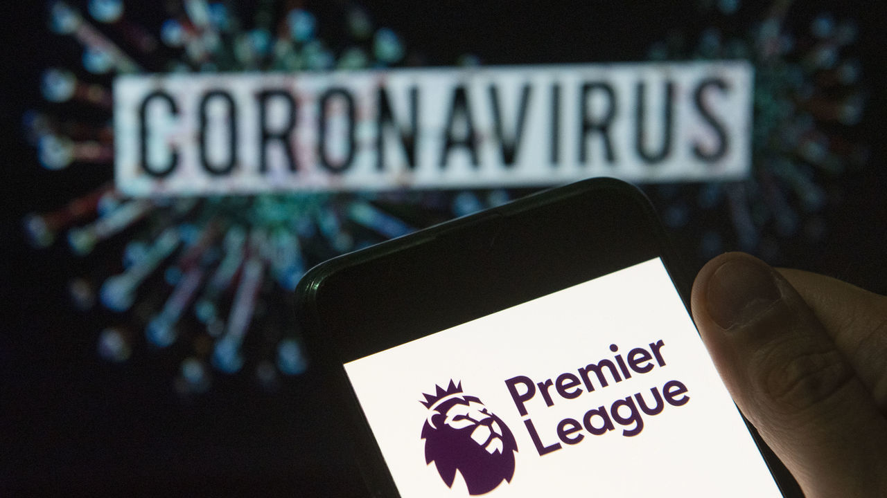 CHINA - 2020/03/24: In this photo illustration the top level of the English football league Premier League logo seen displayed on a smartphone with a computer model of the COVID-19 coronavirus on the background. (Photo Illustration by Budrul Chukrut/SOPA Images/LightRocket via Getty Images)