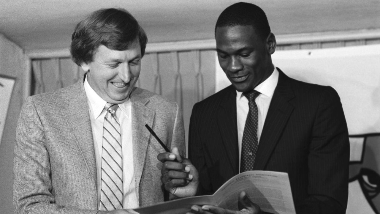 (Original Caption) Michael Jordan, former North Carolina star, College Player of the Year and star of the US Olympic gold medal winning team, looks over the multi-million dollar contract he signed with the Chicago Bulls as Bulls general manager Rod Thorn, (left) looks on 9/12. Jordan was the Bulls first round draft pick in the college draft.