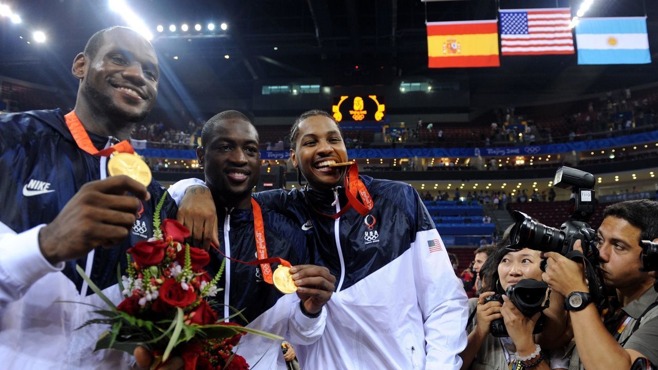 (HR) ABOVE: Carmelo Anthony, right, bites down on his medal with teammates Dwyane Wade, middle and Lebron James, left. The U.S. men's basketball team won the gold medal at the Beijing 2008 Olympic Games with a 118-107 victory over Spain Sunday afternoon at the Olympic Basketball Gymnasium. Spain had closed to within two, 91-89, early in the fourth quarter, but the U.S. responded with a 27-18 surge to close out the victory. Dwyane Wade (Robbins, Ill.) led the U.S. offense with 27 points as the Americans had five players reach double figures in scoring. Kobe Bryant (Ardmore, Pa.) contributed 20 while LeBron James (Akron, Ohio) had 14 and Carmelo Anthony (Baltimore, Md.) and Chris Paul (Clemmons, N.C.) each scored 13. The medal is the 109th of the Beijing 2008 Olympic Games for Team USA, its most in a full participation Olympic Games. The gold medal is the 36th for the United States in Beijing, matching the total received at the Athens 2004 Olympic Games. Helen H. Richardson/The Denver Post