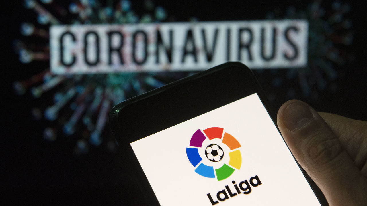 CHINA - 2020/03/24: In this photo illustration the Spanish professional football league La Liga logo seen displayed on a smartphone with a computer model of the COVID-19 coronavirus on the background. (Photo Illustration by Budrul Chukrut/SOPA Images/LightRocket via Getty Images)