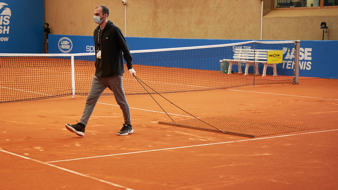 01 May 2020, Rhineland-Palatinate, Höhr-Grenzhausen: Tennis: A tournament staff member wears a face mask while preparing the court for the next match. Although the event is not an official event of the ATP Tour, it is at least a first small step back to a normal life in tennis. Due to the coronavirus pandemic, the worldwide tour is currently suspended until 13 July. Photo: Thomas Frey/dpa