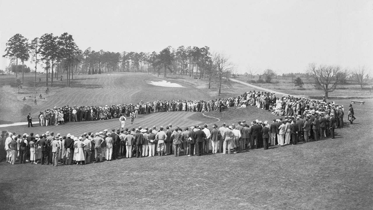 (Original Caption) Bobby Jones Resumes Golf After Four Year Absence. Augusta, Georgia: Ending a four year absence from golf, Bobby Jones returned in the Masters' Invitation Tournament at the Augusta Golf Club in Augusta, Ga. Above is a general view as Bobby putted on the eighteenth green with the crowd watching.