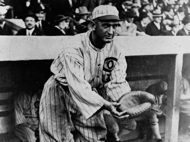 Shoeless Joe Jackson holds out his glove in front of the White Sox dugout.