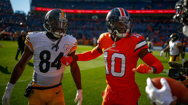 DENVER, CO - NOVEMBER 25: Wide receiver Emmanuel Sanders #10 of the Denver Broncos talks with wide receiver JuJu Smith-Schuster #19 and wide receiver Antonio Brown #84 of the Pittsburgh Steelers as players warm up before a game at Broncos Stadium at Mile High on November 25, 2018 in Denver, Colorado.