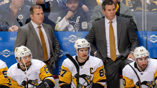 WINNIPEG, MB - NOVEMBER 27: Dominik Simon #12, Assistant Coach Mark Recchi, Sidney Crosby #87, Head Coach Mike Sullivan and Garrett Wilson #10 of the Pittsburgh Penguins look on from the bench during second period action against the Winnipeg Jets at the Bell MTS Place on November 27, 2018 in Winnipeg, Manitoba, Canada.