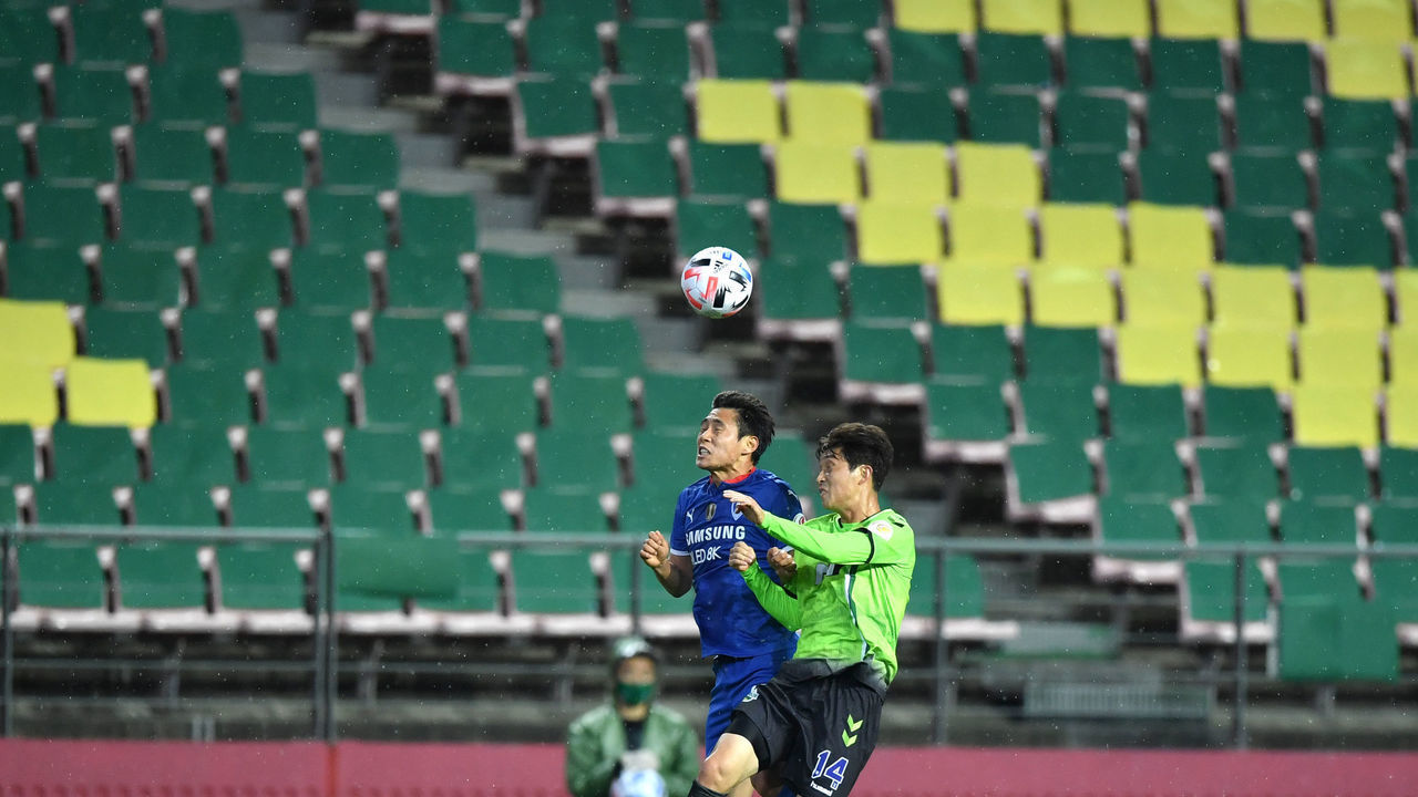 Jeonbuk Hyundai Motors' Lee Seung-gi (R) fights for the ball with Suwon Samsung Bluewings' Myung Joon-jae (L) during the opening game of South Korea's K-League football match at Jeonju World Cup Stadium in Jeonju on May 8, 2020. - The towering stands of the 42,477-capacity Jeonju World Cup Stadium stood empty on May 8 as South Korea opened football's post-coronavirus era without fans, but with an unprecedented international TV audience.