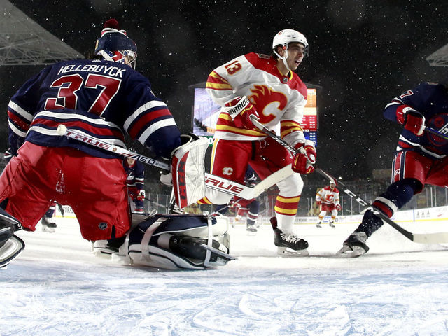 REGINA, SASKATCHEWAN - OCTOBER 26: Goaltender Connor Hellebuyck #37 of the Winnipeg Jets defends the net against Johnny Gaudreau #13 of the Calgary Flames during the 2019 Tim Hortons NHL Heritage Classic at Mosaic Stadium on October 26, 2019 in Regina, Canada.