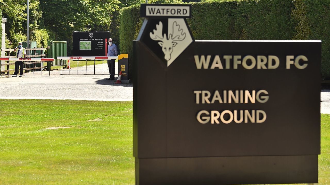 Security guards wearing PPE (personal protective equipment) man a gate at Watford's training facility at London Colney, in north London on May 20, 2020 as training continues for Premier League clubs with a June re-start the intention during the COVID-19 pandemic. - Teams have started socially-distanced training in small groups this week, but several Premier League stars have expressed concerns about plans to resume the season.