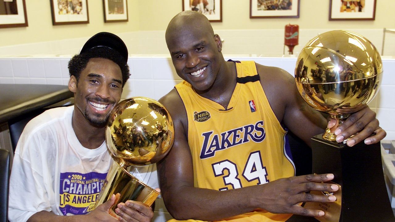 Kobe Bryant (L) of the Los Angeles Lakers holds the Larry O'Brian trophy as teammate Shaquille O'Neal (L) hold the MVP trophy after winning the NBA Championship against Indiana Pacers 19 June, 2000, after game six of the NBA Finals at Staples Center in Los Angeles, CA. The Lakers won the game 116-111 to take the NBA title 4-2 in the best-of-seven series. (ELECTRONIC IMAGE) AFP PHOTO