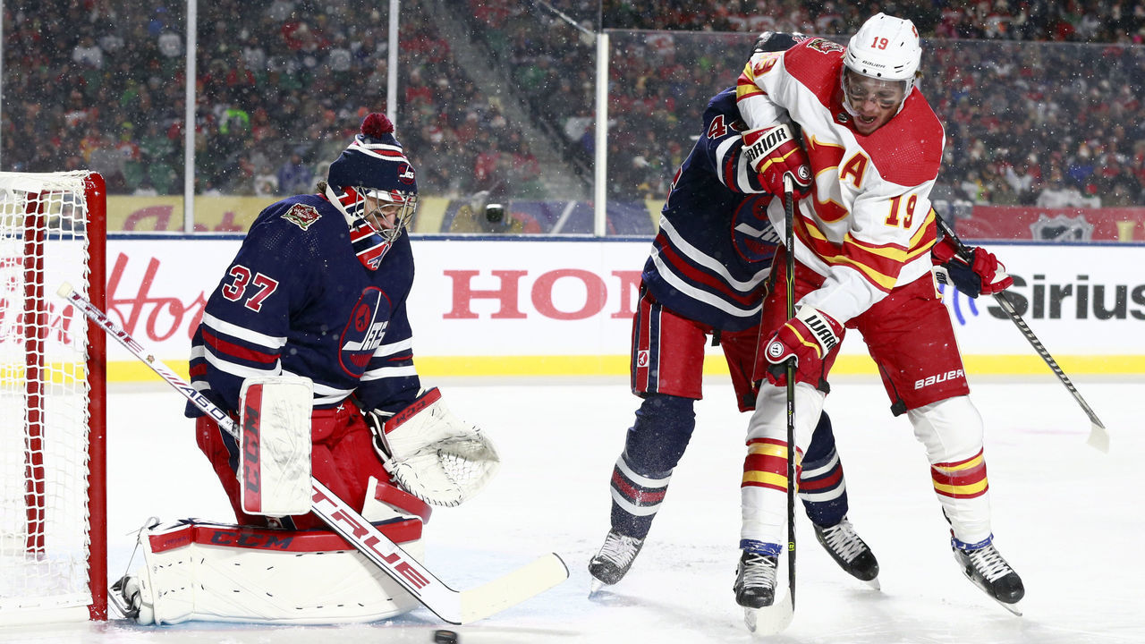 REGINA, SASKATCHEWAN - OCTOBER 26: Goaltender Connor Hellebuyck #37 of the Winnipeg Jets makes a save on a scoring attempt by Matthew Tkachuk #19 of the Calgary Flames in the first period of the 2019 Tim Hortons NHL Heritage Classic between the Calgary Flames and the Winnipeg Jets at Mosaic Stadium on October 26, 2019 in Regina, Canada.