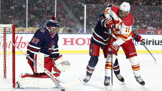 REGINA, SASKATCHEWAN - OCTOBER 26: Goaltender Connor Hellebuyck #37 of the Winnipeg Jets makes a save on a scoring attempt by Matthew Tkachuk #19 of the Calgary Flames in the first period of the 2019 Tim Hortons NHL Heritage Classic between the Calgary Flames and the Winnipeg Jets at Mosaic Stadium on October 26, 2019 in Regina, Canada.