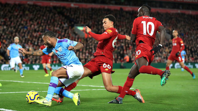 Manchester City's Raheem Sterling (left) goes down under pressure from Liverpool's Trent Alexander-Arnold and Sadio Mane (right) during the Premier League match at Anfield, Liverpool.