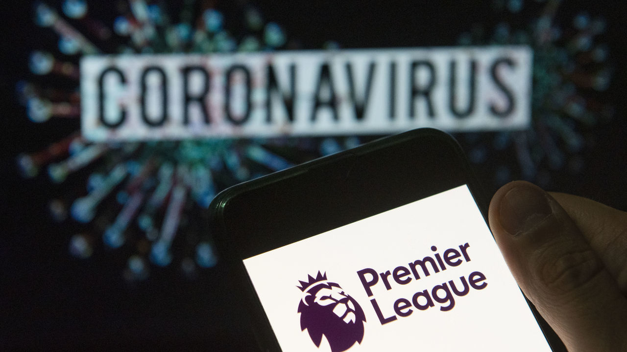 CHINA - 2020/03/24: In this photo illustration the top level of the English football league Premier League logo seen displayed on a smartphone with a computer model of the COVID-19 coronavirus on the background. (Photo Illustration by Budrul Chukrut/SOPA Images/LightRocket via Getty Images)
