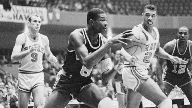 (Original Caption) Chicago Packers Wally Bellamy, (#8) charges toward his end of the court after retrieving the ball from Hawks Bob Pettit, (#9), in the first quarter action here. Hawk Shellie McMillon, (#25) made an unsuccessful try for the ball. Packer Andy Johnson, (#12) is shown in the background.