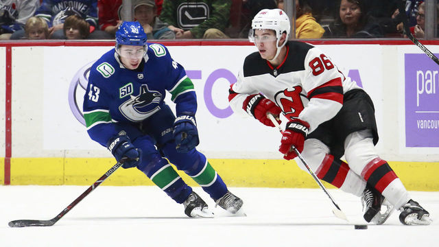 VANCOUVER, BC - NOVEMBER 10: Quinn Hughes #43 of the Vancouver Canucks looks on as Jack Hughes #86 of the New Jersey Devils skates up ice with the puck during their NHL game at Rogers Arena November 10, 2019 in Vancouver, British Columbia, Canada. "n