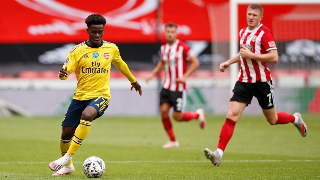 Arsenal's English striker Bukayo Saka (L) runs with the ball during the English FA Cup quarter-final football match between Sheffield United and Arsenal at Bramall Lane in Sheffield, northern England on June 28, 2020.