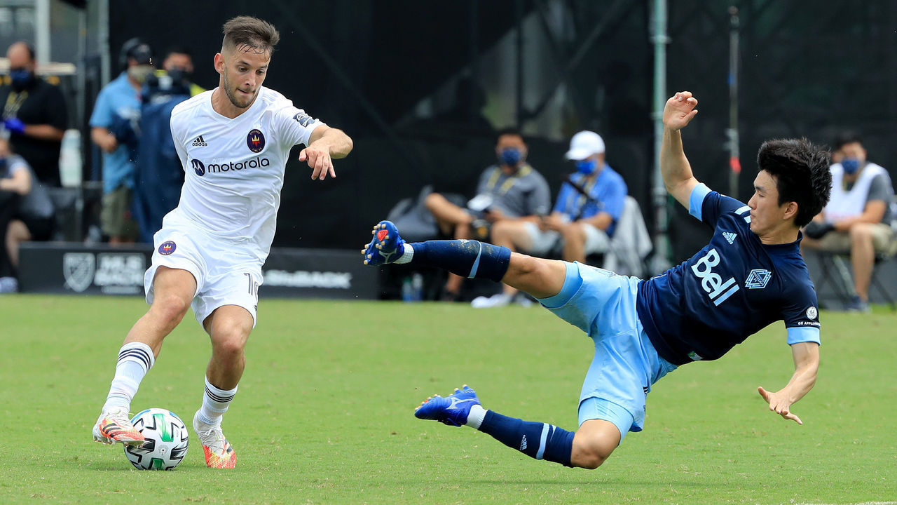 REUNION, FLORIDA - JULY 23: Hwang In-Beom #6 of Vancouver Whitecaps attempts to tackle Alvaro Medran #10 of Chicago Fire during a Group B match of the MLS Is Back Tournament at ESPN Wide World of Sports Complex on July 23, 2020 in Reunion, Florida.