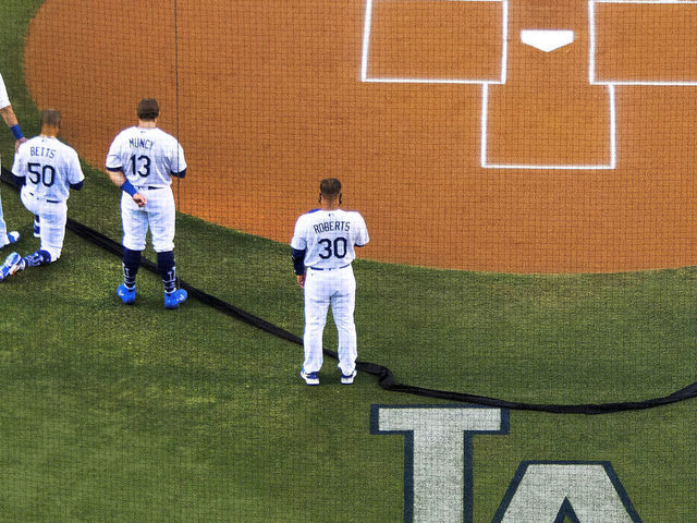 MLB - Mookie Betts takes a knee during the National Anthem, supported by  teammates Cody Bellinger and Max Muncy.