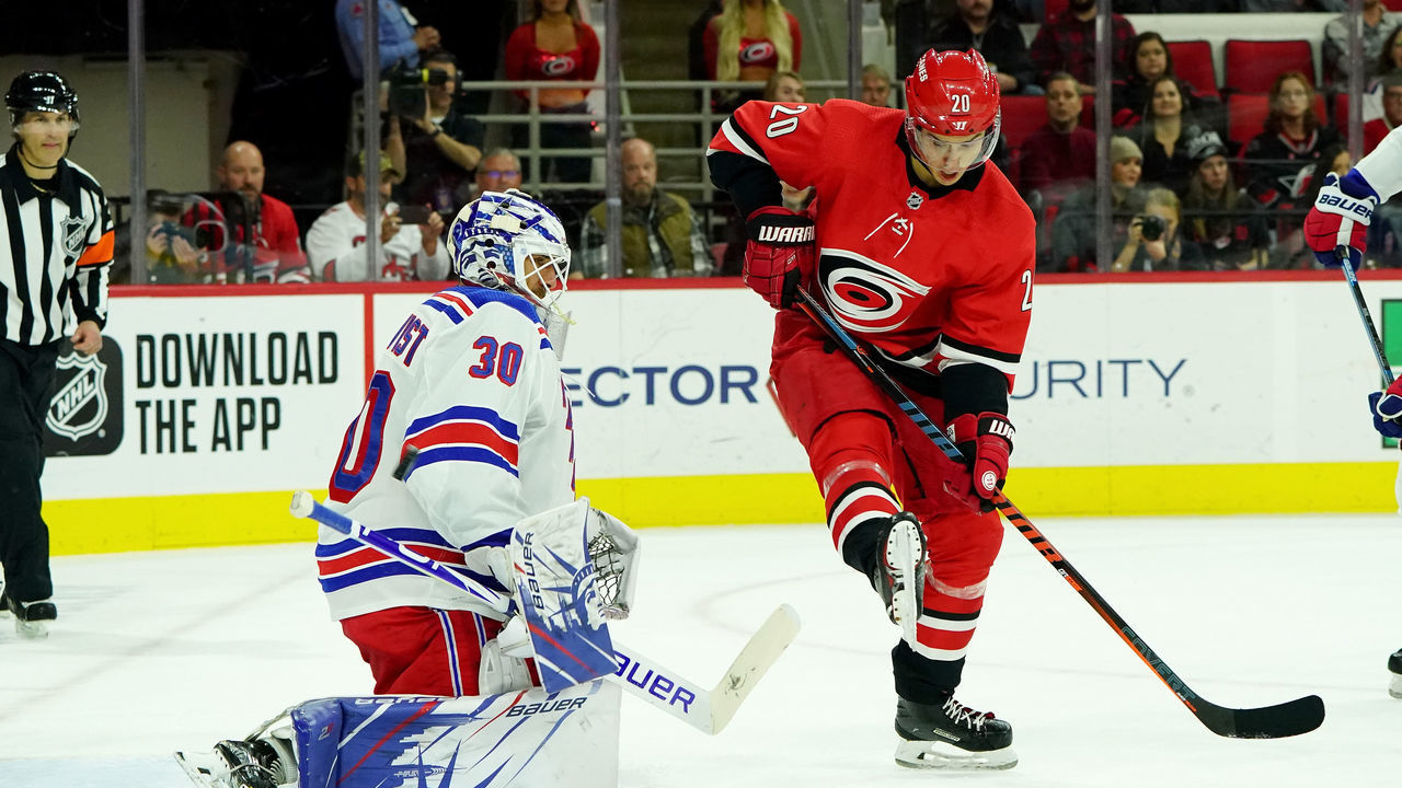 RALEIGH, NC - NOVEMBER 7: Sebastian Aho #20 of the Carolina Hurricanes creates traffic in front of Henrik Lundqvist #30 of the New York Rangers who goes down in the crease to protect the net during an NHL game on November 7, 2019 at PNC Arena in Raleigh, North Carolina.