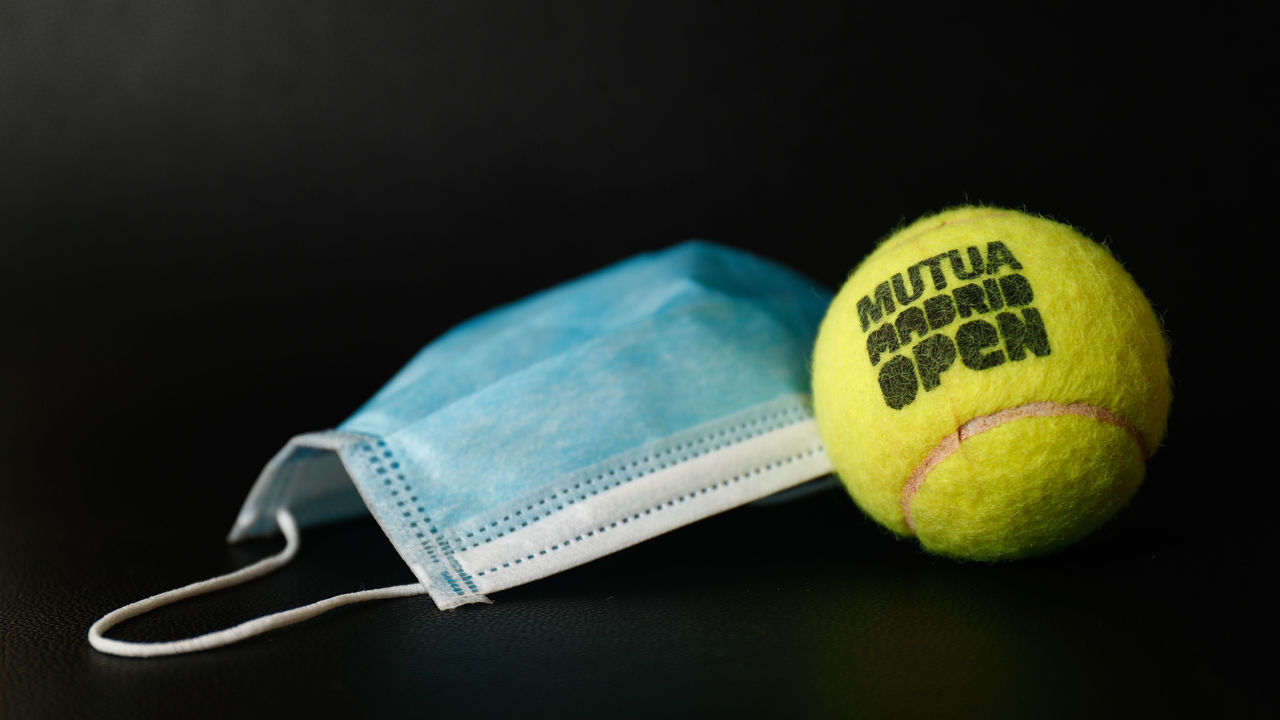 MADRID, SPAIN - APRIL 27: An official ball from the Mutua Madrid Open professional tennis tournament together with a surgical mask. The competition will be 'played' virtually from today to 30th April from the players' homes. In parallel with the official tournament, a charity event will take place that will pit professional tennis players against some of the main content creators in the gaming territory to raise funds to help those affected by the Covid-19, thanks to the participation of Webedia on April 27, 2020 in Madrid, Spain.