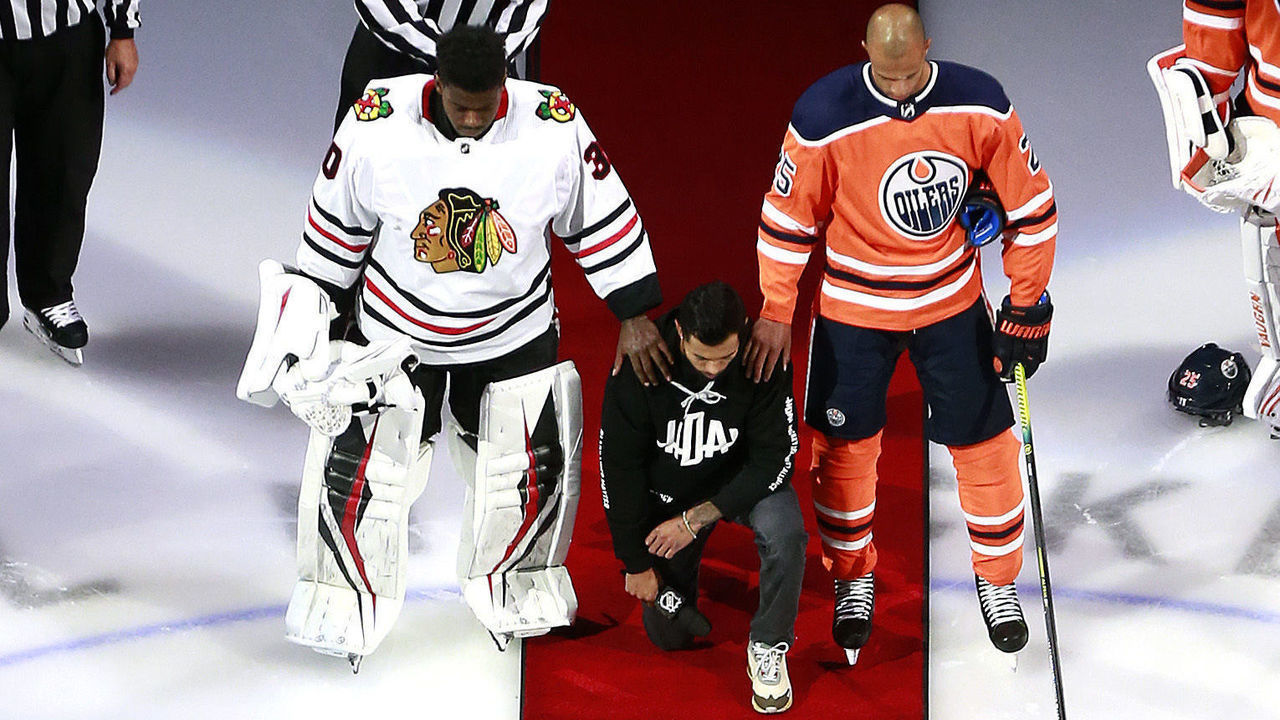 EDMONTON, ALBERTA - AUGUST 01: Malcolm Subban #30 of the Chicago Blackhawks and Darnell Nurse #25 of the Edmonton Oilers place their hands on Mathew Dumba of the Minnesota Wild during the national anthem of the United States before the Game One of the Eastern Conference Qualification Round prior to the 2020 NHL Stanley Cup Playoffs at Rogers Place on August 01, 2020 in Edmonton, Alberta.Dumba spoke before the game about the NHL's support of Black Lives Matter and ending racism.