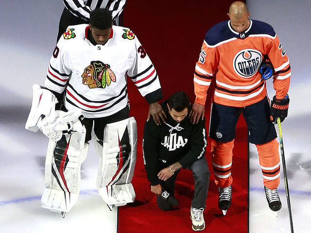 EDMONTON, ALBERTA - AUGUST 01: Malcolm Subban #30 of the Chicago Blackhawks and Darnell Nurse #25 of the Edmonton Oilers place their hands on Mathew Dumba of the Minnesota Wild during the national anthem of the United States before the Game One of the Eastern Conference Qualification Round prior to the 2020 NHL Stanley Cup Playoffs at Rogers Place on August 01, 2020 in Edmonton, Alberta.Dumba spoke before the game about the NHL's support of Black Lives Matter and ending racism.