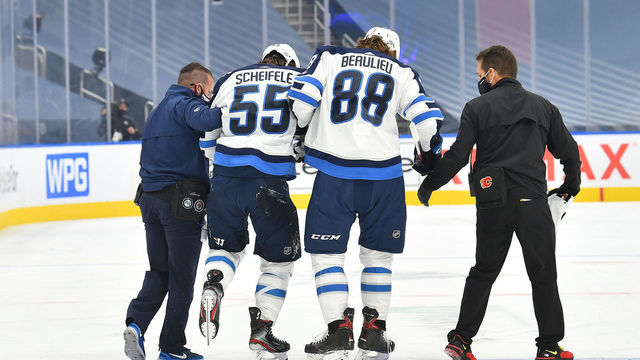 EDMONTON, ALBERTA - AUGUST 01: Mark Scheifele #55 of the Winnipeg Jets is helped off the ice by teammate Nathan Beaulieu #88 and team trainers in the first period of Game One of the Western Conference Qualification Round against the Calgary Flames prior to the 2020 NHL Stanley Cup Playoffs at Rogers Place on August 01, 2020 in Edmonton, Alberta.