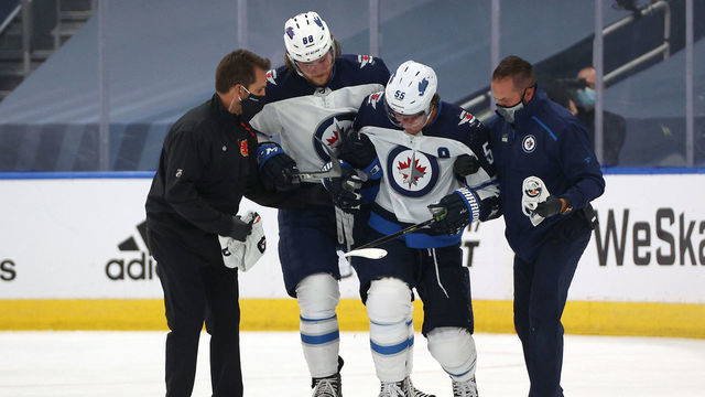 EDMONTON, ALBERTA - AUGUST 01: Mark Scheifele #55 of the Winnipeg Jets is helped off the ice by teammate Nathan Beaulieu #88 and team trainers after Scheifele suffered a leg injury in the first period of Game One of the Western Conference Qualification Round against the Calgary Flames prior to the 2020 NHL Stanley Cup Playoffs at Rogers Place on August 01, 2020 in Edmonton, Alberta.