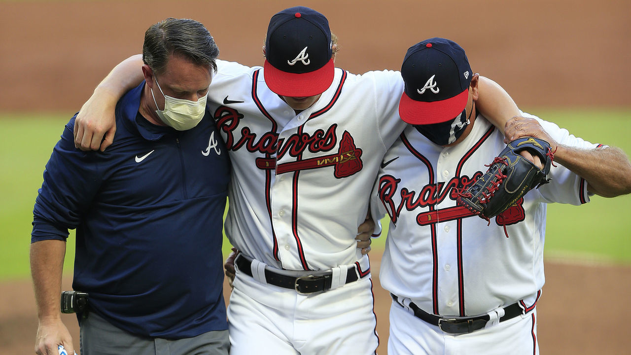 ATLANTA, GA - AUGUST 03: A member of the Braves training staff and manager Brian Snitker (r) help Atlanta Braves starting pitcher Mike Soroka off the field after he injures his right leg during the MLB game between the Atlanta Braves and the New York Mets on August 03, 2020 at Truist Park in Atlanta, Georgia.