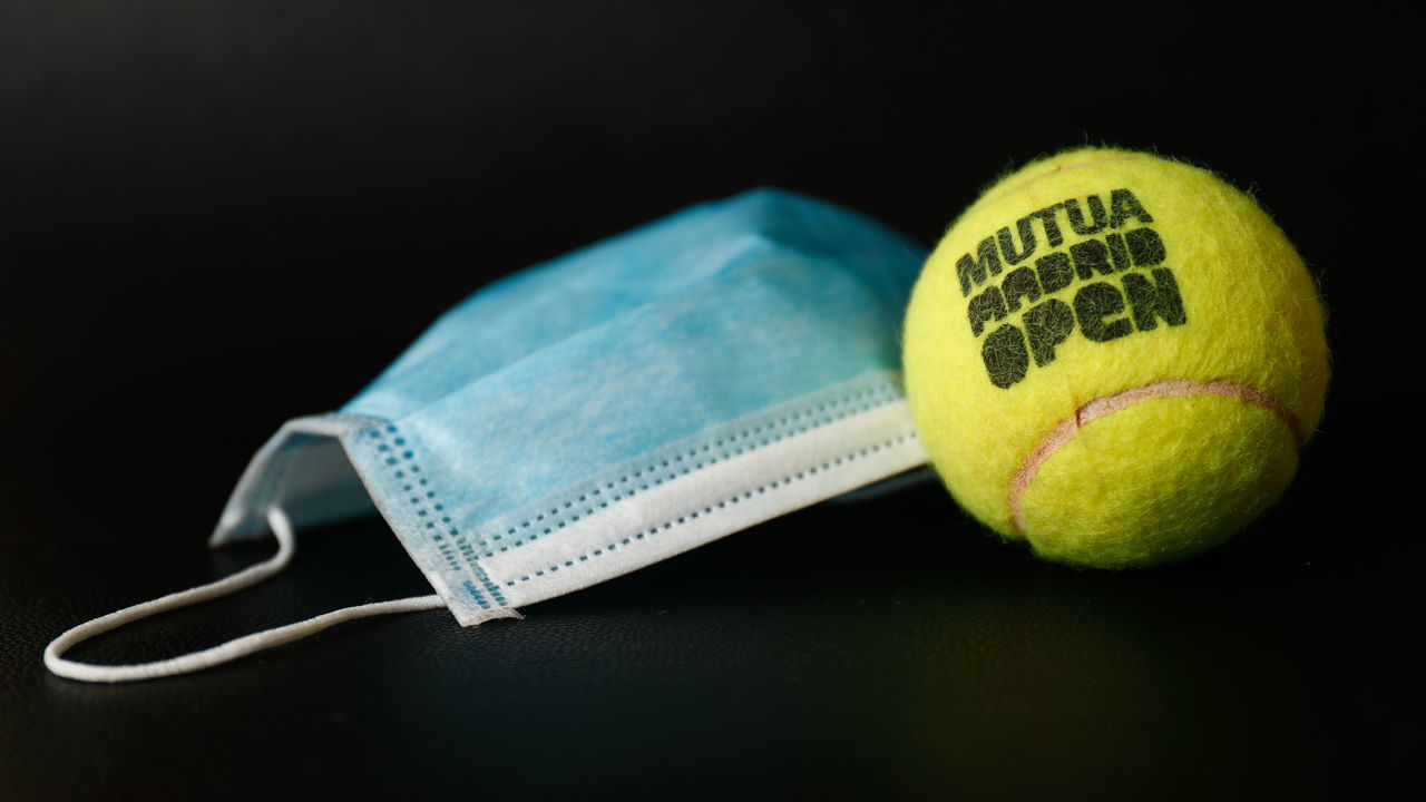 MADRID, SPAIN - APRIL 27: An official ball from the Mutua Madrid Open professional tennis tournament together with a surgical mask. The competition will be 'played' virtually from today to 30th April from the players' homes. In parallel with the official tournament, a charity event will take place that will pit professional tennis players against some of the main content creators in the gaming territory to raise funds to help those affected by the Covid-19, thanks to the participation of Webedia on April 27, 2020 in Madrid, Spain.