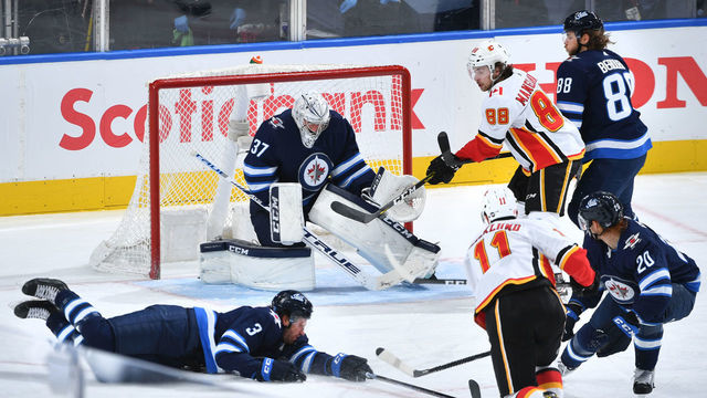 EDMONTON, ALBERTA - AUGUST 04: Mikael Backlund #11 of the Calgary Flames takes a shot against goaltender Connor Hellebuyck #37 of the Winnipeg Jets but is blocked by Tucker Poolman #3 during the second period of Game Three of the Western Conference Qualification Round at Rogers Place on August 04, 2020 in Edmonton, Alberta.