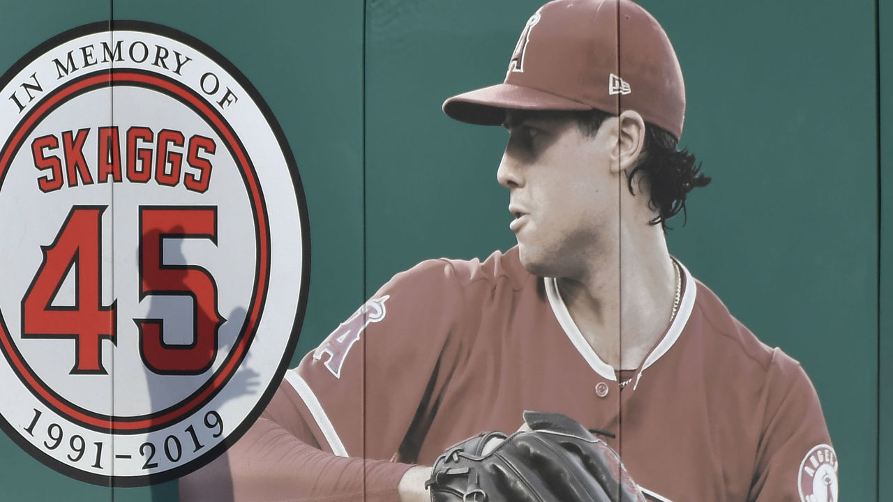 ANAHEIM, CA - SEPTEMBER 27: Hansel Robles #57 of the Los Angeles Angels looks at a ball as it goes over the wall and a photo of Tyler Skaggs #45 during batting practice before playing the Houston Astros at Angel Stadium of Anaheim on September 27, 2019 in Anaheim, California.