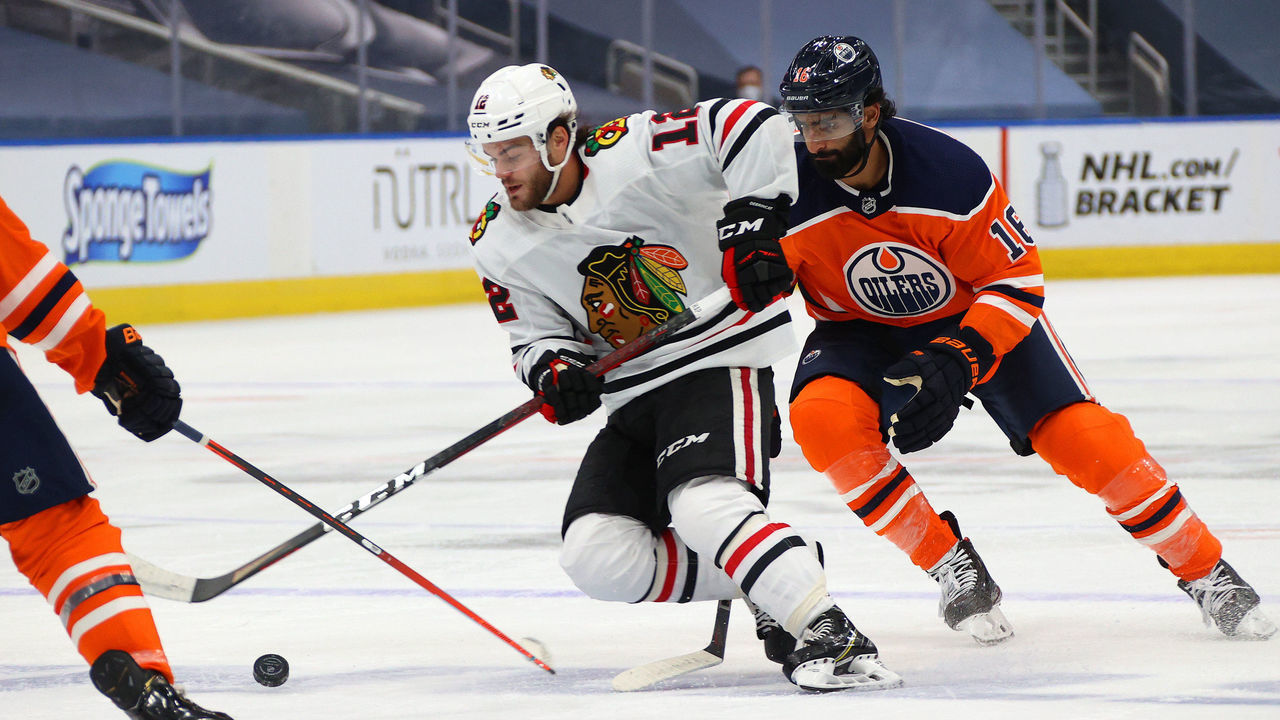 EDMONTON, ALBERTA - AUGUST 03: Alex DeBrincat #12 of the Chicago Blackhawks and Jujhar Khaira #16 of the Edmonton Oilers skate in the second period of Game Two of the Western Conference Qualification Round prior to the 2020 NHL Stanley Cup Playoffs at Rogers Place on August 03, 2020 in Edmonton, Alberta.