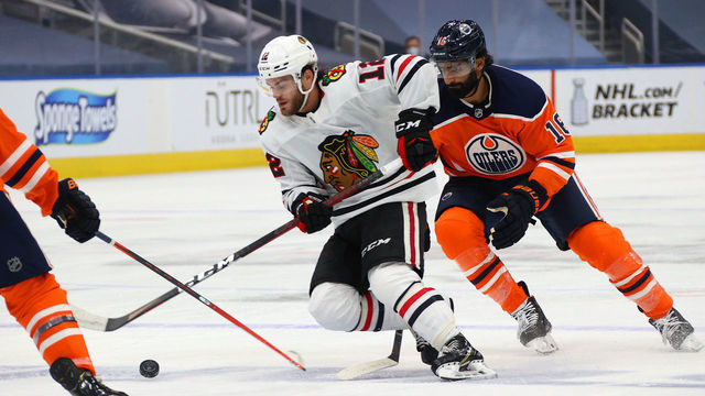 EDMONTON, ALBERTA - AUGUST 03: Alex DeBrincat #12 of the Chicago Blackhawks and Jujhar Khaira #16 of the Edmonton Oilers skate in the second period of Game Two of the Western Conference Qualification Round prior to the 2020 NHL Stanley Cup Playoffs at Rogers Place on August 03, 2020 in Edmonton, Alberta.