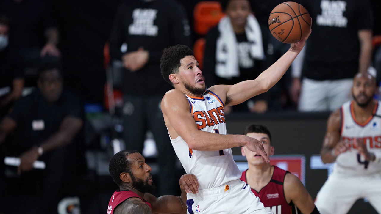 LAKE BUENA VISTA, FLORIDA - AUGUST 08: Devin Booker #1 of the Phoenix Suns drives to the basket past Andre Iguodala #28 of the Miami Heat during the second half of an NBA game at Visa Athletic Center at ESPN Wide World Of Sports Complex on August 8, 2020 in Lake Buena Vista, Florida.