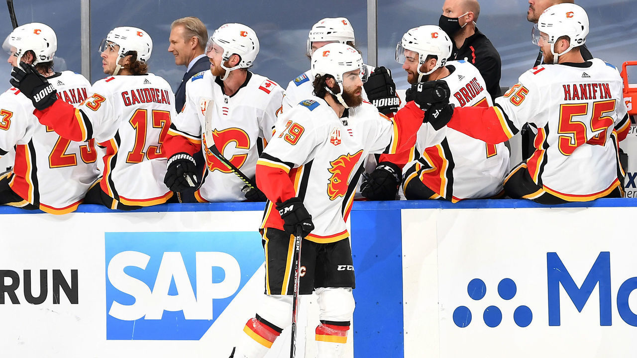 EDMONTON, ALBERTA - AUGUST 11: Dillon Dube #29 of the Calgary Flames skates by the bench to celebrate with teammates after Dube scored his second goal in the first period during Game One of the Western Conference First Round of the 2020 NHL Stanley Cup Playoff against the Dallas Stars at Rogers Place on August 11, 2020 in Edmonton, Alberta.
