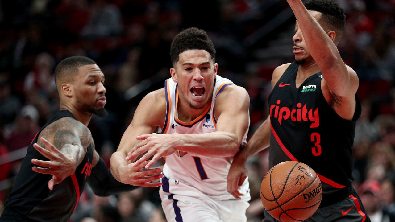 PORTLAND, OR - MARCH 09: Devin Booker #1 of the Phoenix Suns loses the ball against Damian Lillard #0 (L) and CJ McCollum #3 of the Portland Trail Blazers in the third quarter during their game at Moda Center on March 9, 2019 in Portland, Oregon.
