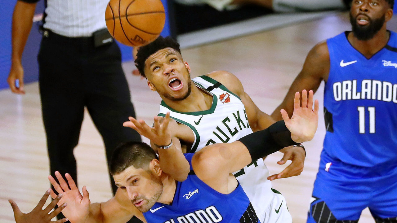 LAKE BUENA VISTA, FLORIDA - AUGUST 18: Giannis Antetokounmpo #34 of the Milwaukee Bucks fouls Nikola Vucevic #9 of the Orlando Magic while reaching for a loose ball in the second half during Game One in the first round of the NBA playoffs at The Field House at ESPN Wide World Of Sports Complex on August 18, 2020 in Lake Buena Vista, Florida. NOTE TO USER: User expressly acknowledges and agrees that, by downloading and/or using this Photograph, user is consenting to the terms and conditions of the Getty Images License Agreement.