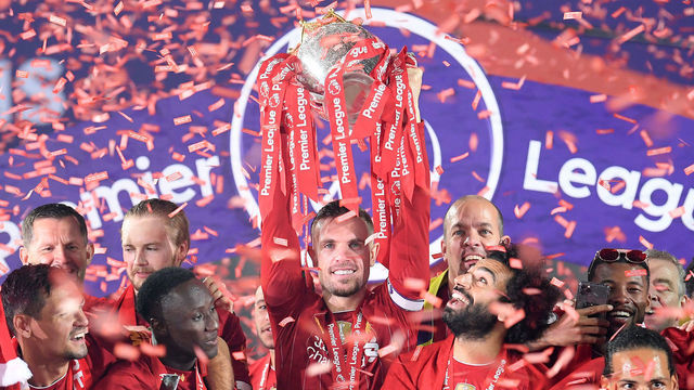 LIVERPOOL, ENGLAND - JULY 22: Jordan Henderson of Liverpool holds the Premier League Trophy aloft along side Mohamed Salah as they celebrate winning the League during the presentation ceremony of the Premier League match between Liverpool FC and Chelsea FC at Anfield on July 22, 2020 in Liverpool, England. Football Stadiums around Europe remain empty due to the Coronavirus Pandemic as Government social distancing laws prohibit fans inside venues resulting in games being played behind closed doors.
