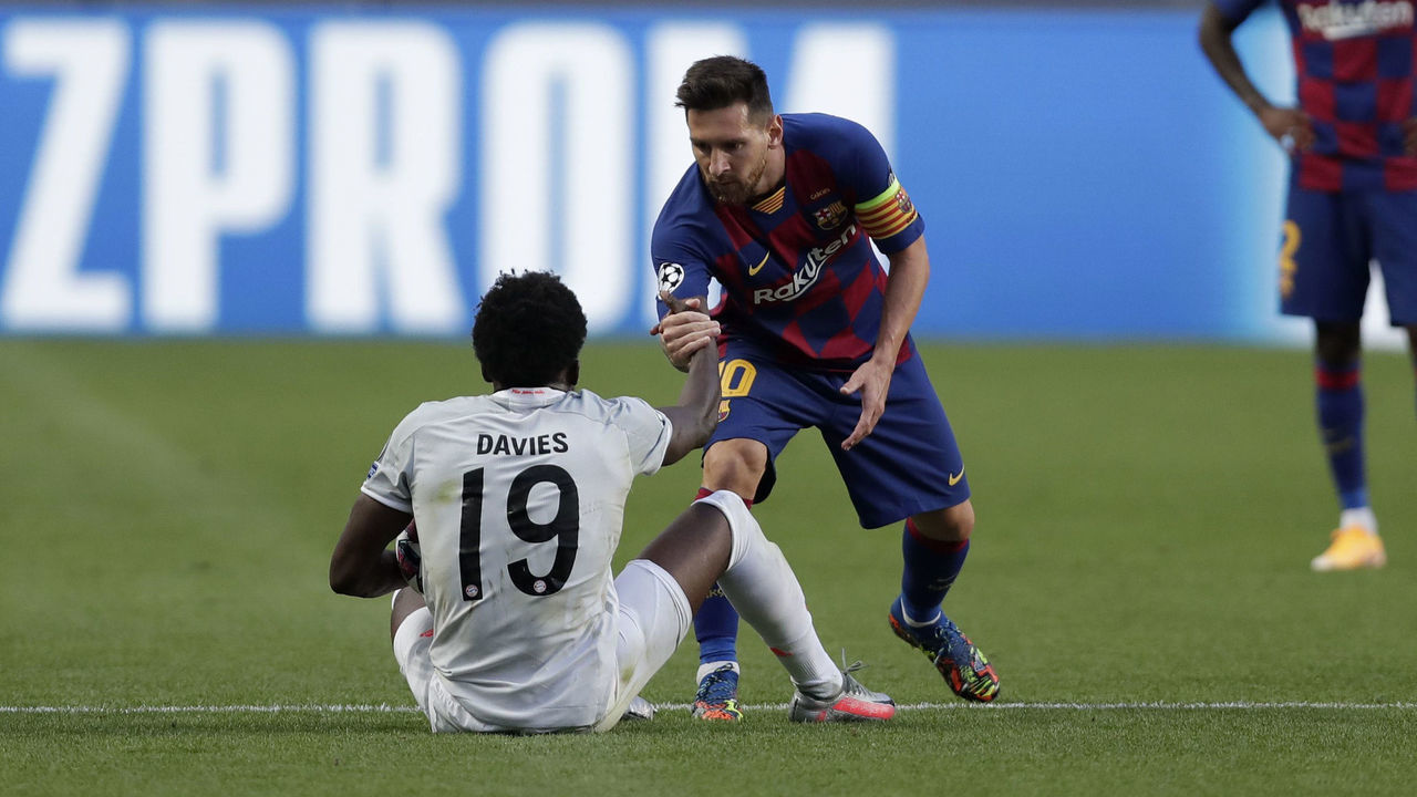 LISBON, PORTUGAL - AUGUST 14: Lionel Messi of FC Barcelona helps Alphonso Davies of FC Bayern Munich to his feet after a challenge during the UEFA Champions League Quarter Final match between Barcelona and Bayern Munich at Estadio do Sport Lisboa e Benfica on August 14, 2020 in Lisbon, Portugal.
