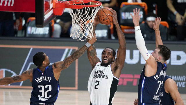 LAKE BUENA VISTA, FLORIDA - AUGUST 23: Los Angeles Clippers' Kawhi Leonard #2 goes up for a shot as Dallas Mavericks Trey Burke #32 and Luka Doncic #77 defend during the second half of an NBA basketball first round playoff game at AdventHealth Arena at ESPN Wide World Of Sports Complex on August 23, 2020 in Lake Buena Vista, Florida.