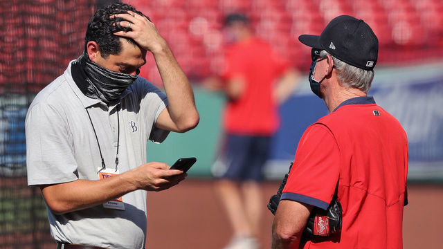 BOSTON - JULY 27: With the COVID-19 scare impacting baseball, Chief Baseball Officer Chaim Bloom, left, has an animated chat with manager Ron Roenicke, right, during batting practice. The Boston Red Sox host the New York Mets in an MLB regular season baseball game at Fenway Park in Boston during the coronavirus pandemic on July 27, 2020.