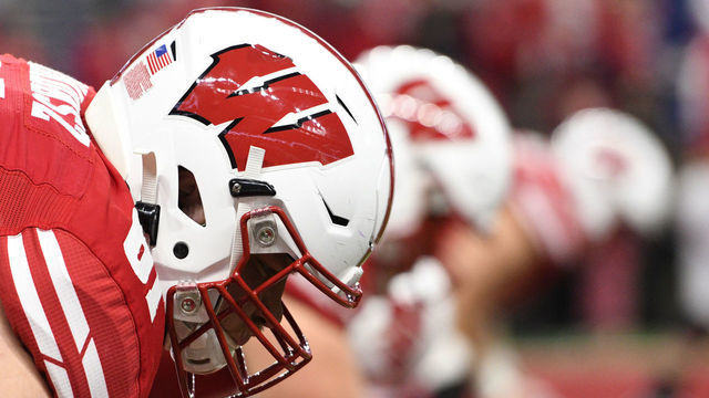 INDIANAPOLIS, IN - DECEMBER 07: A Wisconsin Badgers helmet is seen as Wisconsin Badgers offensive lineman Tyler Biadasz (61) warms up for the Big Ten Conference Championship football game between the Wisconsin Badgers and the Ohio State Buckeyes on December 7, 2019, at Lucas Oil Stadium in Indianapolis, Indiana.