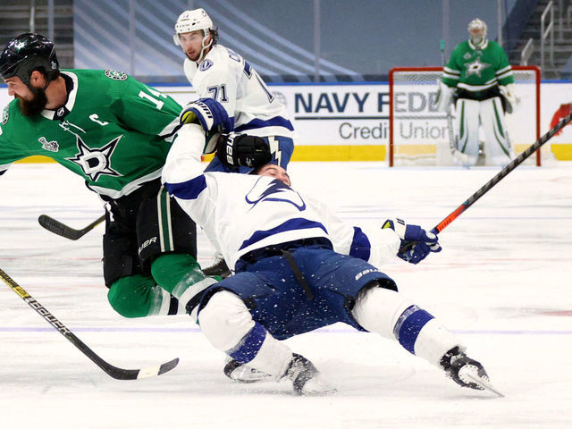 EDMONTON, ALBERTA - SEPTEMBER 25: Jamie Benn #14 of the Dallas Stars takes down Tyler Johnson #9 of the Tampa Bay Lightning in the first overtime period of Game Four of the NHL Stanley Cup Final between the Tampa Bay Lightning and the Dallas Stars at Rogers Place on September 25, 2020 in Edmonton, Alberta, Canada. Benn was given a two-minute minor penalty for tripping for the take down of Johnson.
